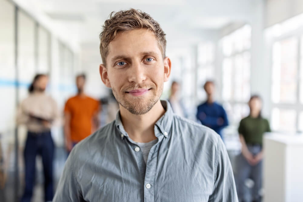 Freundlicher Mann im Büro mit Team im Hintergrund